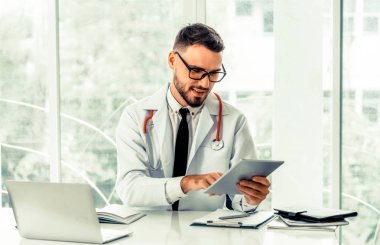 Hastanede tablet bilgisayar üzerinde çalışan doktor.