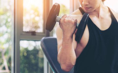 Kaslı adam vücut geliştirmeci dumbbells ile eğitim.