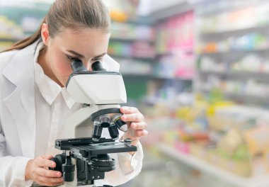 Bilim adamı araştırmacı laboratuvarda mikroskop kullanır