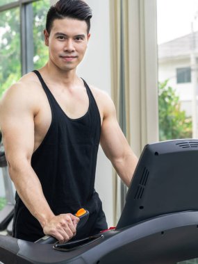 Spor salonunda koşu bandıüzerinde çalışan sportif koşucu.