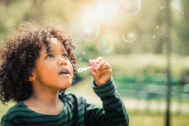 Mutlu küçük çocuk okul bahçesinde kabarcık üfleme.