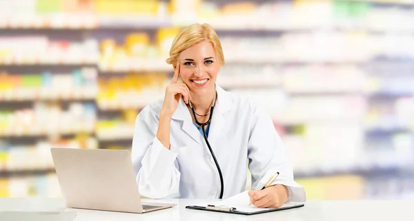 Pharmacist using laptop computer at pharmacy.