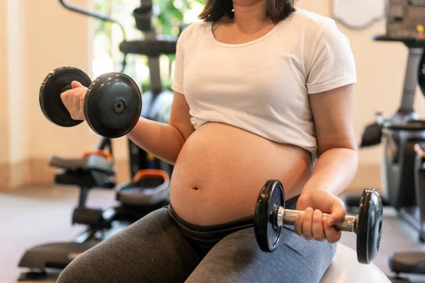 Active pregnant woman exercise in fitness center.