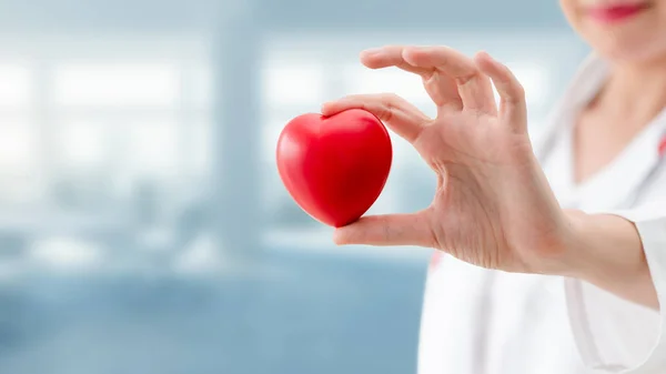 Doctor sosteniendo un corazón rojo en la oficina del hospital . — Foto de Stock