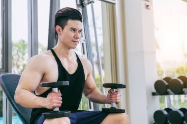 Kaslı adam vücut geliştirmeci dumbbells ile eğitim.