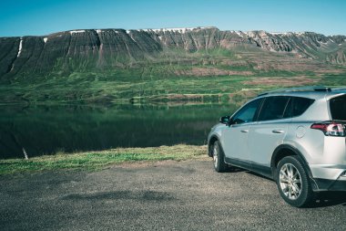 Dağ ile göl tarafında SUV araba park.