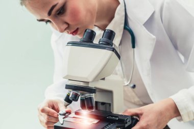 Hastane laboratuvarında mikroskop kullanan doktor.