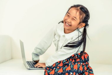 Küçük çocuk beyaz kanepeüzerinde dizüstü bilgisayar kullanarak.