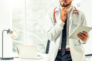 Hastanede tablet bilgisayar üzerinde çalışan doktor.