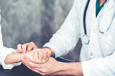 Hastane ofisinde hastayı muayene eden genç doktor.