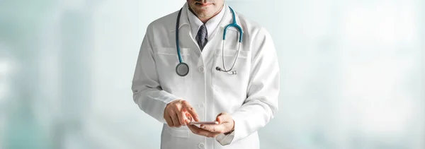 Мужчина врач, использующий мобильный телефон в больнице. — стоковое фото