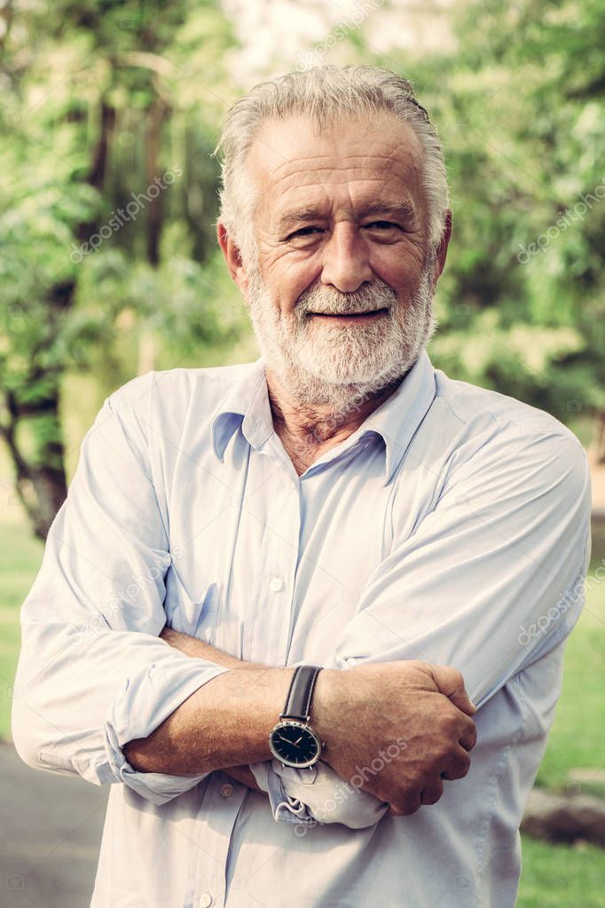 Portrait of happy senior man standing in the park.