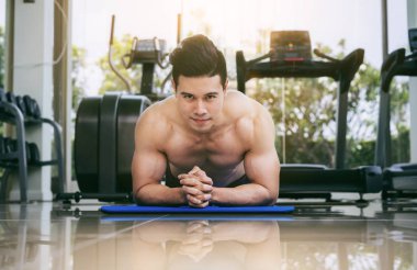 Genç adam vücut geliştirmeci fitness merkezinde itmek.