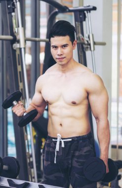 Kaslı adam vücut geliştirmeci dumbbells ile eğitim.