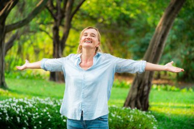 Parkta duran mutlu orta yaşlı kadın.