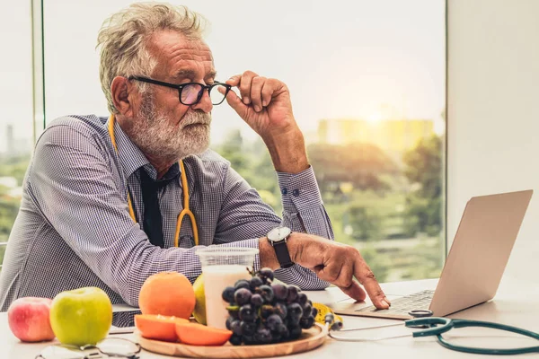 Dizüstü bilgisayar üzerinde çalışan kıdemli erkek beslenme uzmanı doktor. — Stok fotoğraf