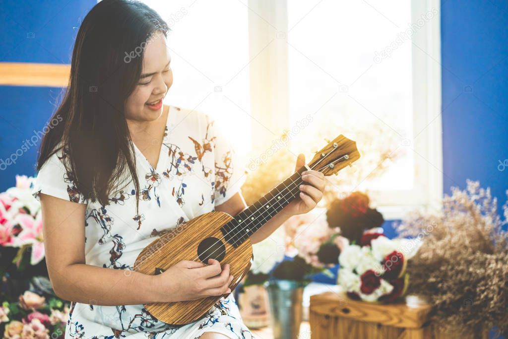 Happy woman musician playing ukulele in studio.