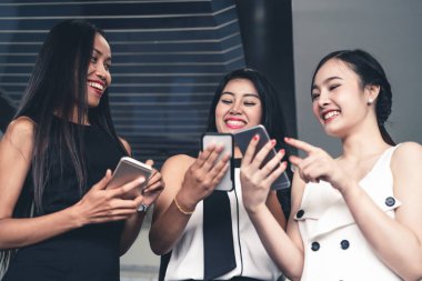 Üç kadın arkadaş cep telefonu aygıtıyla konuşuyor.
