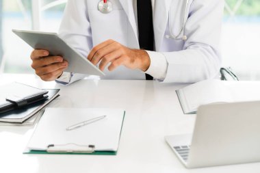 Hastanede tablet bilgisayar üzerinde çalışan doktor.