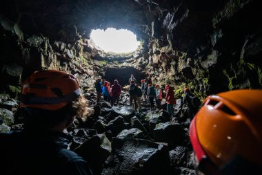 Porlakshafnarvegur, İzlanda - 3 Temmuz 2018: Bir grup insan ve turist İzlanda'daki Raufarholshellir lav tüneli mağarasını keşfediyor. Mağara doğal olarak magma katılaşması ile oluşmuştur..