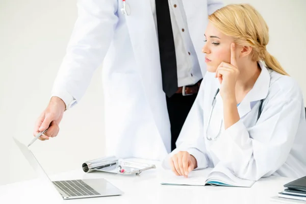 Doctor at hospital works on computer with partner.