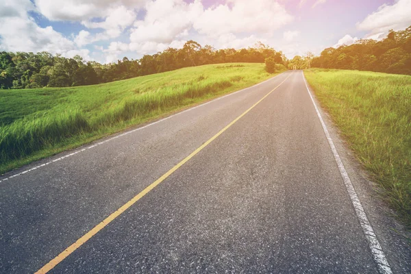 Highway road through green grass under blue sky. — Stock Photo, Image