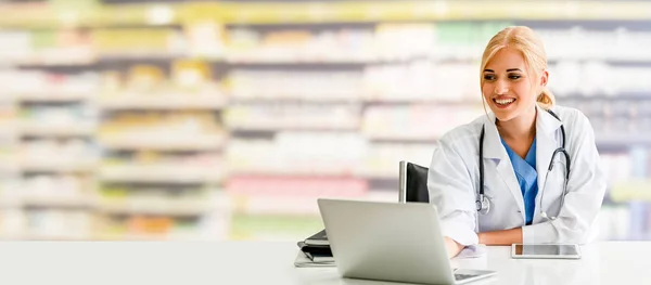 Pharmacist using laptop computer at pharmacy.