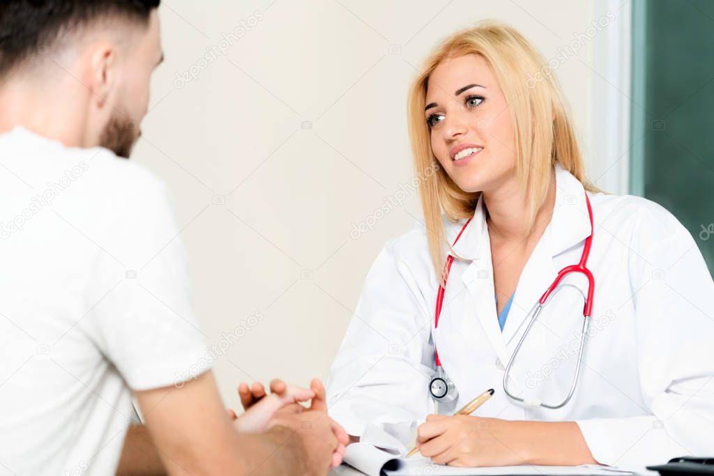 Woman Doctor and Male Patient in Hospital Office