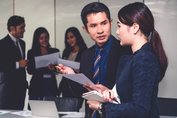 Businessman talking to businesswoman in meeting.