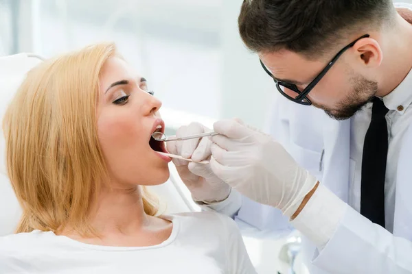 Junge Zahnärztin untersucht Patientin in Zahnklinik. — Stockfoto