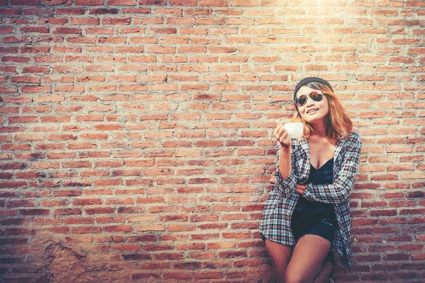 Mutlu genç kadın tuğla duvara karşı duran. — Stok fotoğraf