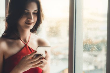 Kahve dükkanında akıllı telefon kullanan mutlu kadın.