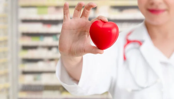 Doctor holding a red heart at hospital office. — Stock Photo, Image