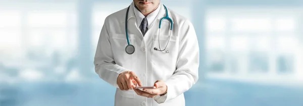 Мужчина врач, использующий мобильный телефон в больнице. — стоковое фото
