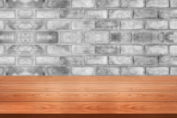 Деревянный стол на фоне размытого фона кирпичной стены . — стоковое фото