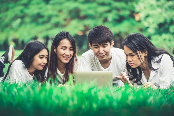 Team of young students studying in a group project in the park of university or school. Happy learning, community teamwork and youth friendship concept.