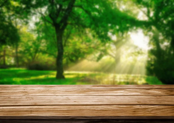 緑のぼかし自然の背景に茶色の木製のテーブル. — ストック写真