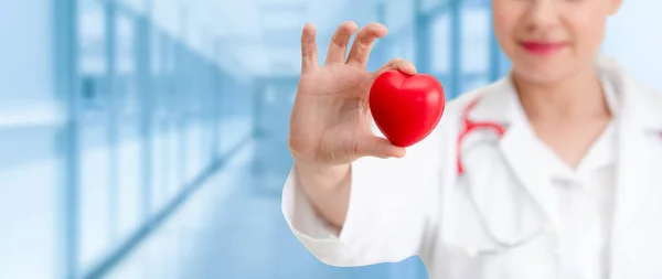 Doctor sosteniendo un corazón rojo en la oficina del hospital . — Foto de Stock