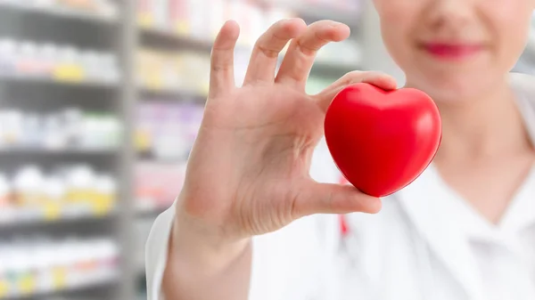 Doctor sosteniendo un corazón rojo en la oficina del hospital . — Foto de Stock