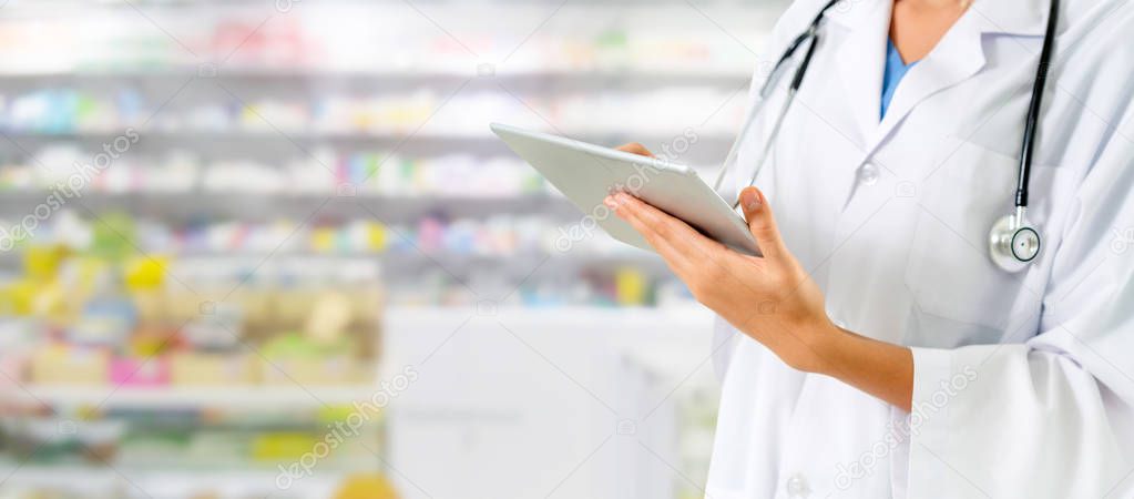 Pharmacist using tablet computer at pharmacy.
