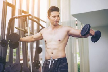 Kaslı adam vücut geliştirmeci dumbbells ile eğitim.