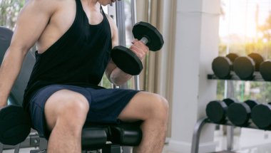 Kaslı adam vücut geliştirmeci dumbbells ile eğitim.