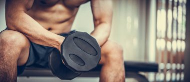 Kaslı adam vücut geliştirmeci dumbbells ile eğitim.