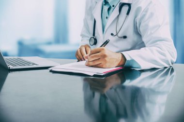 Doktor hastane ofisindeki belgelere yazıyor..