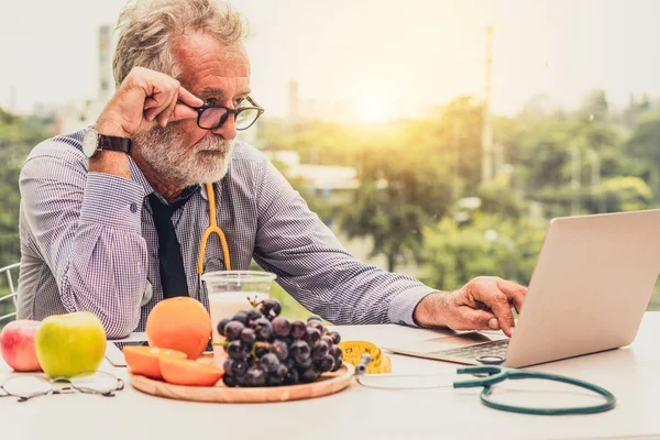 Senior médico nutricionista masculino que trabaja en el ordenador portátil . —  Fotos de Stock