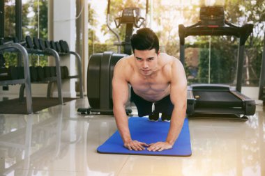 Genç adam vücut geliştirmeci fitness merkezinde itmek.