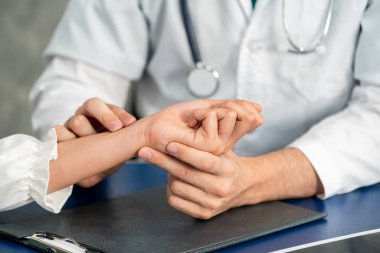 Hastane ofisinde hastayı muayene eden genç doktor.