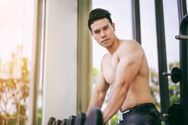 Kaslı adam vücut geliştirmeci dumbbells ile eğitim.