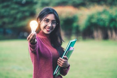 Yaratıcı genç kadın parlayan ampul tutun.