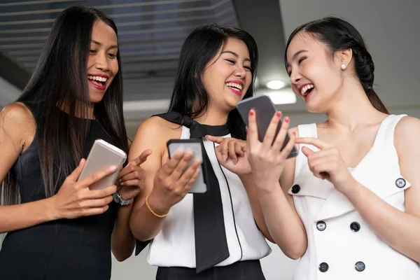 Three women friends chat with mobile phone device.